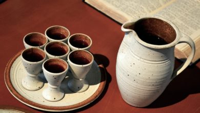 Ein Krug der Alkohol in Form von Wein beinhaltet neben einer Bibel
