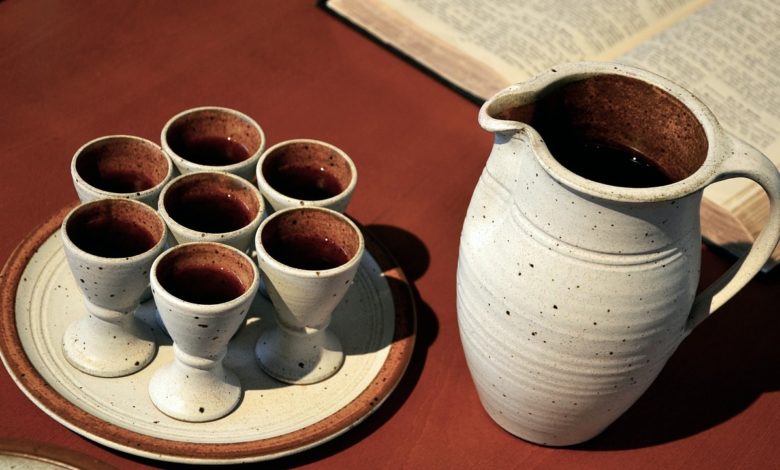 Ein Krug der Alkohol in Form von Wein beinhaltet neben einer Bibel