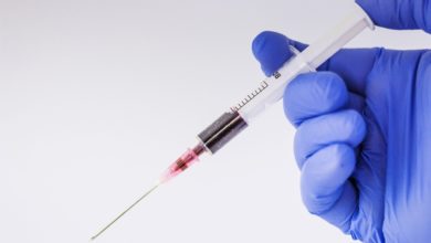 Eine Hand, die eine Spritze gefüllt mit Blut hält bei einer Blutspende oder Bluttransfusion, die gegen die Bibel ist