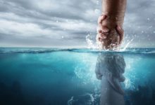 Eine Hand, die eine andere aus dem Wasser rettet, symbolisch für die Taufe mit Wasser in der Bibel